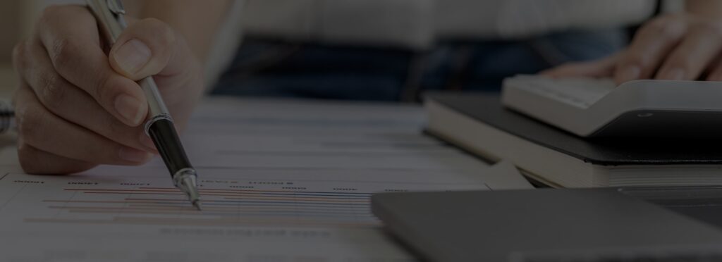 A hand with a pen points at a document with charts, highlighting credit report fraud. Nearby, books and a laptop suggest an analysis.